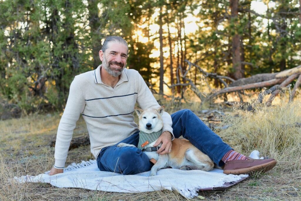 Thomas of Mr. Woof sitting with a dog outdoors in Denver