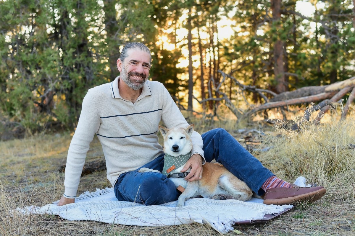 Thomas of Mr. Woof sitting with a dog outdoors in Denver